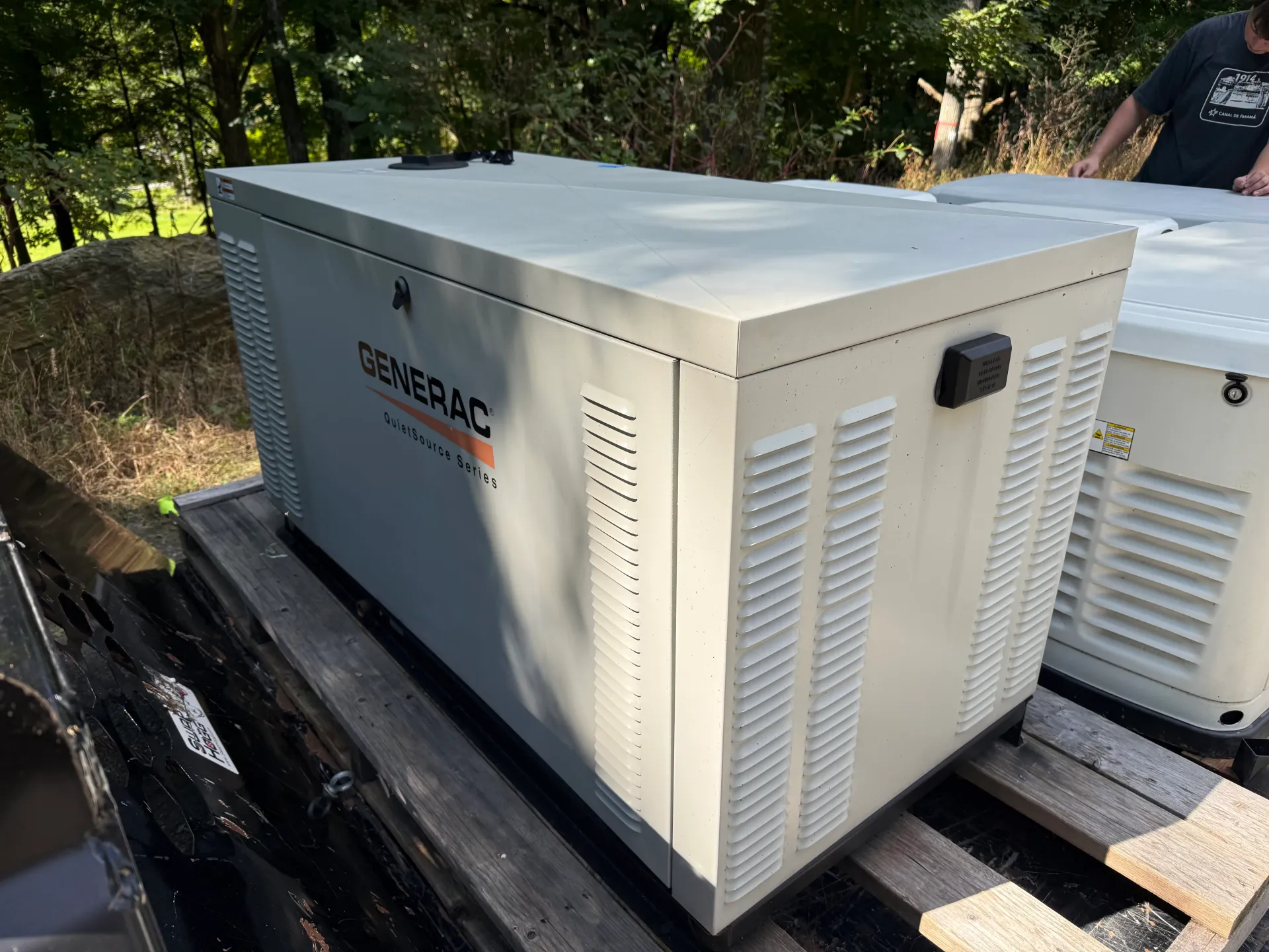 White Generac liquid-cooled generator on a trailer, photographed outdoors with another generator behind it
